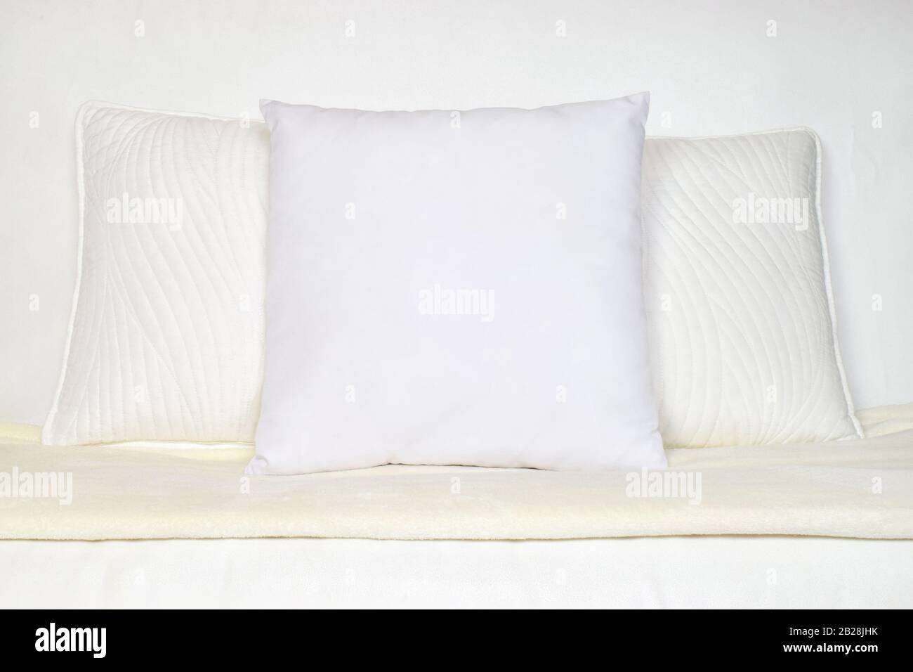 White Throw Pillow Mockup on Plush White Couch Stock Photo