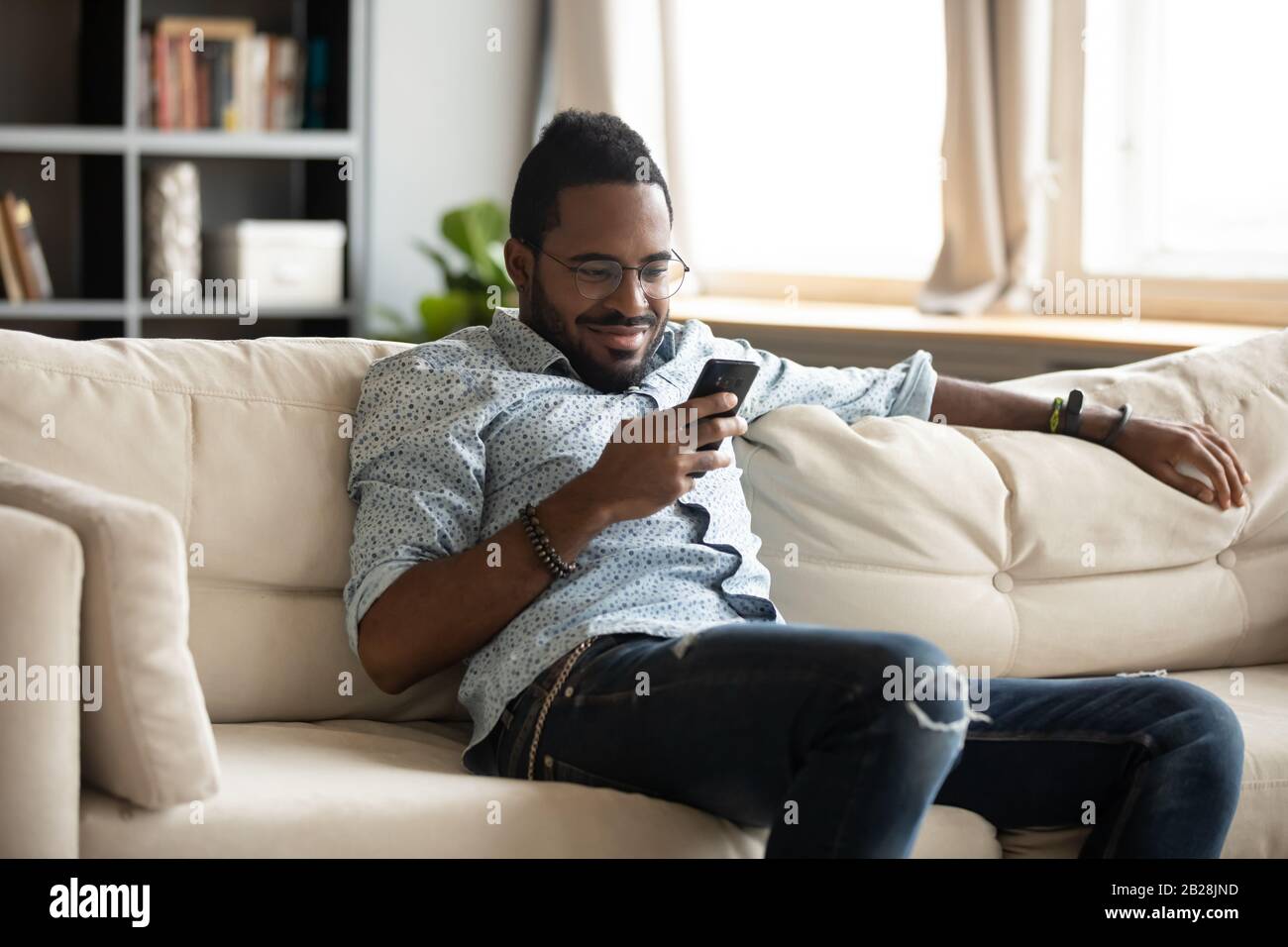 Smiling young biracial man using mobile applications. Stock Photo