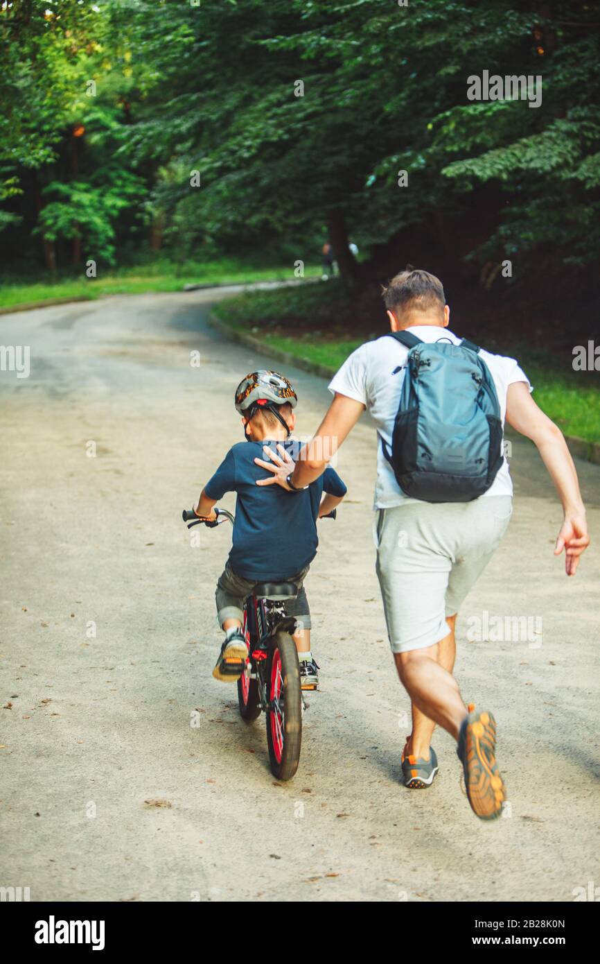 father teaching son how to ride bicycle Stock Photo