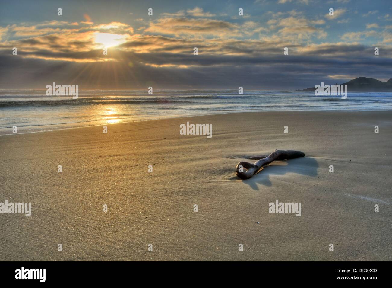 Orange Sun Setting behind the clouds framing the Pacific Ocean horizon