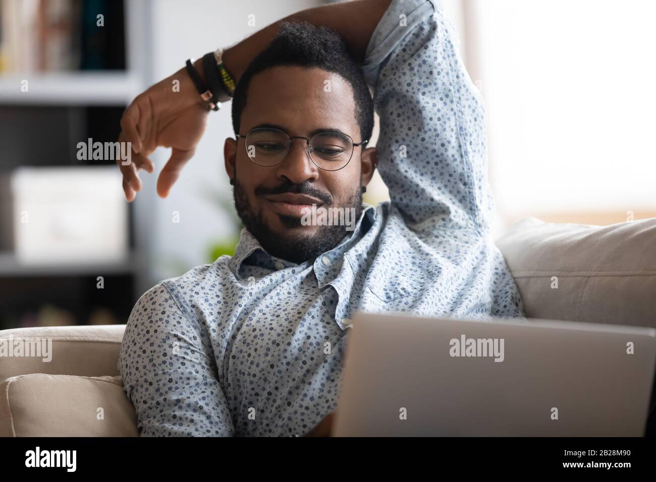 Happy multiracial guy chatting online with friends, enjoying free time. Stock Photo