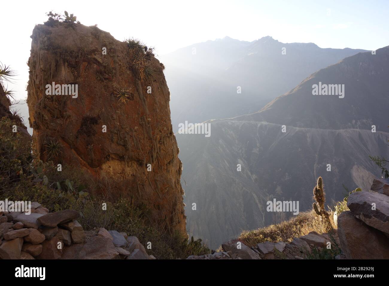 Single big rock in front of deep Colca canyon (Canon de Colca) in Peru with foggy mountains on trekkingroute Cabanaconde to Sangalle Oasis Stock Photo