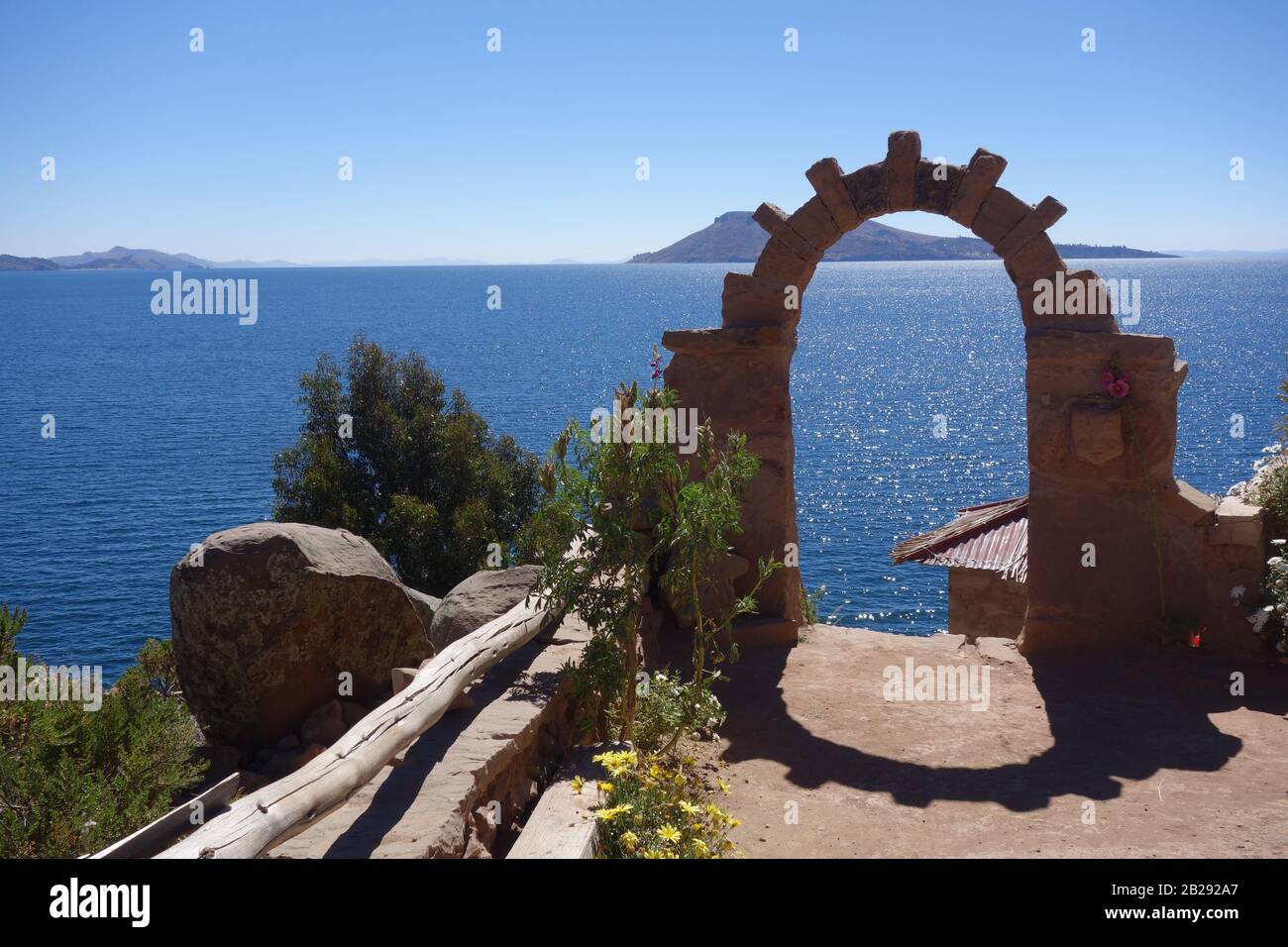 Island Amantani on Titicaca lake in Peru Bolivia close to Puno - view with beautiful scenery of stone arc arch and bright deep blue lake on sunny day Stock Photo