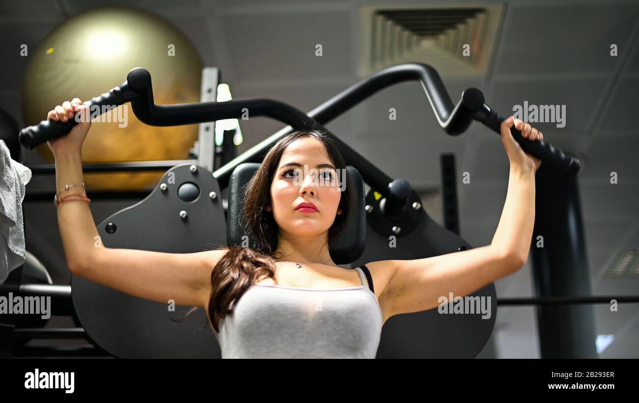 Woman using a chest press machine in a gym Stock Photo - Alamy