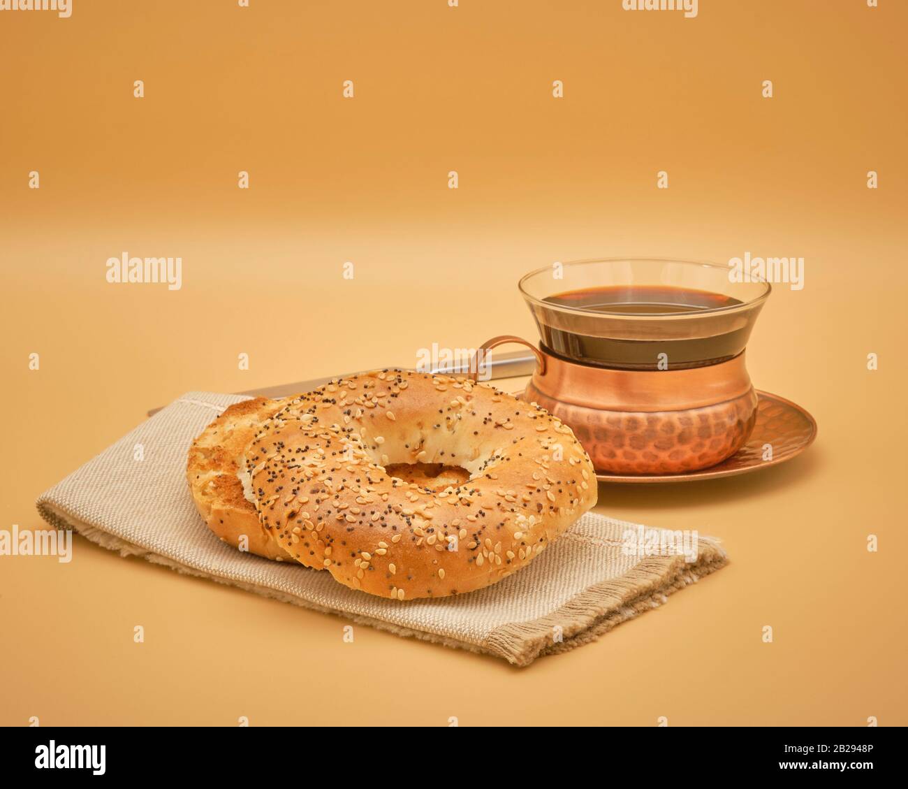 Variety of bagel commonly known as the everything bagel as it it a complex mix of ingredients and flavours is toasted and served with coffee. Stock Photo