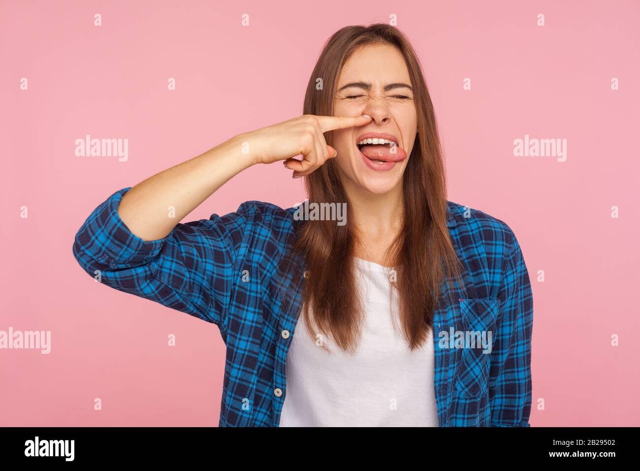 Portrait of girl in checkered shirt picking nose pulling out boogers with disgust expression, bad manners concept and misconduct, uncultured gross hab Stock Photo