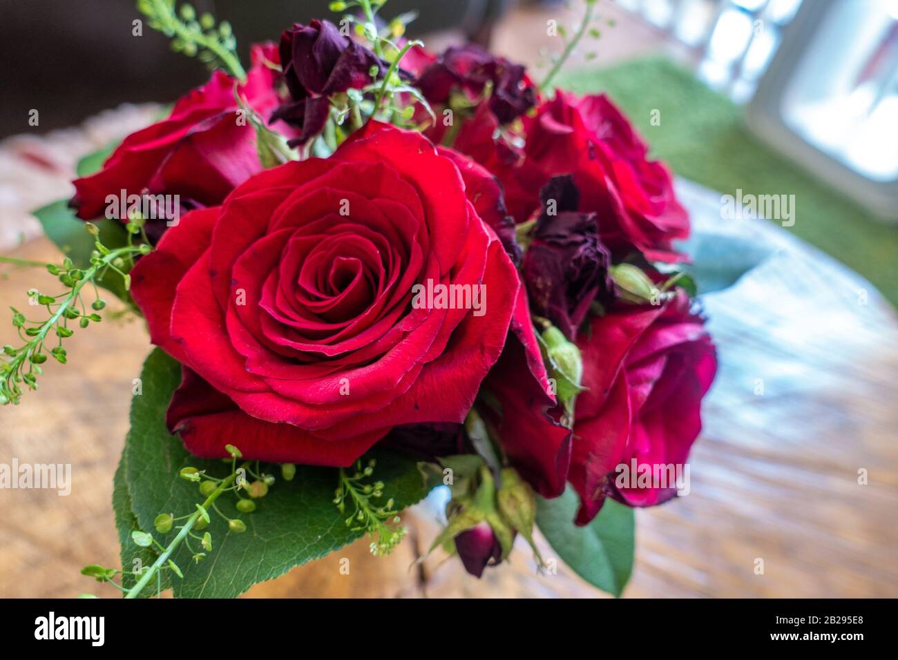A small vase of red roses and other flowers form a decorative centrepiece Stock Photo Alamy