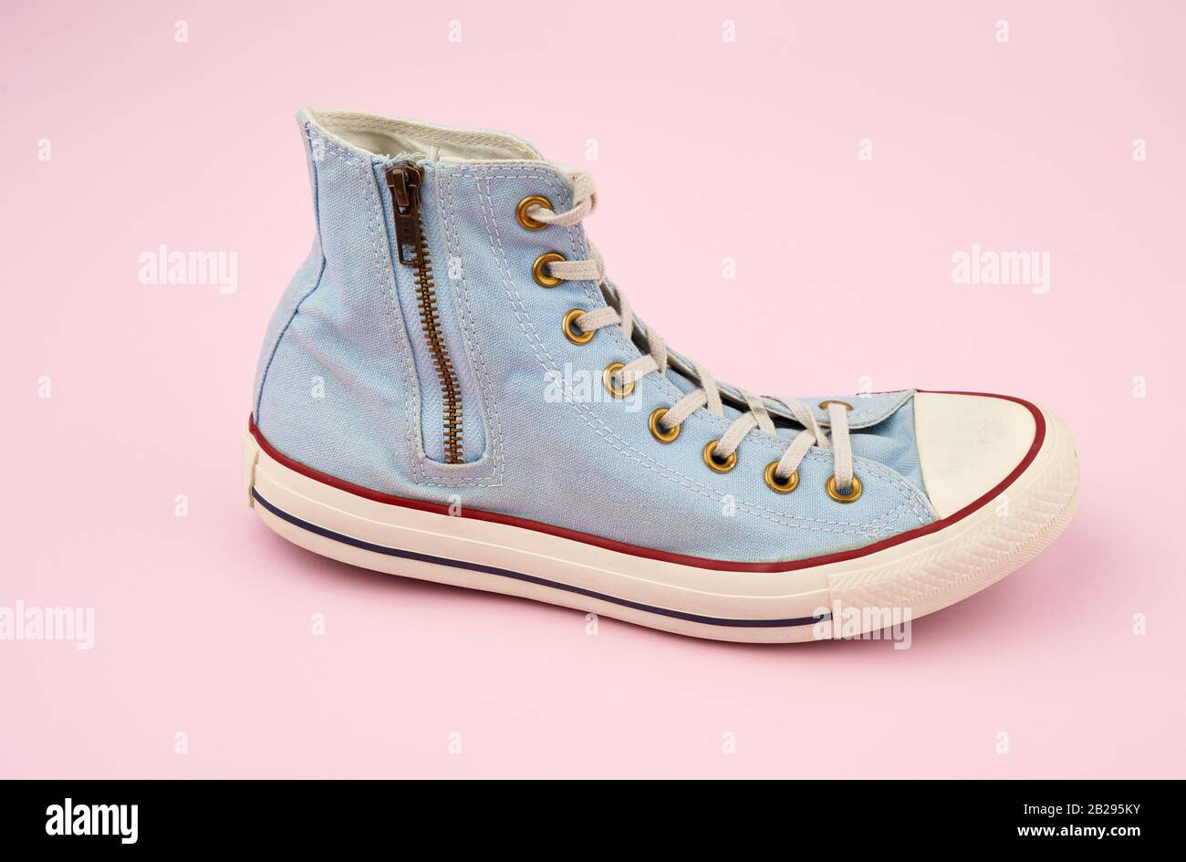 light blue worn textile sneaker with laces and zippers on a pink ...