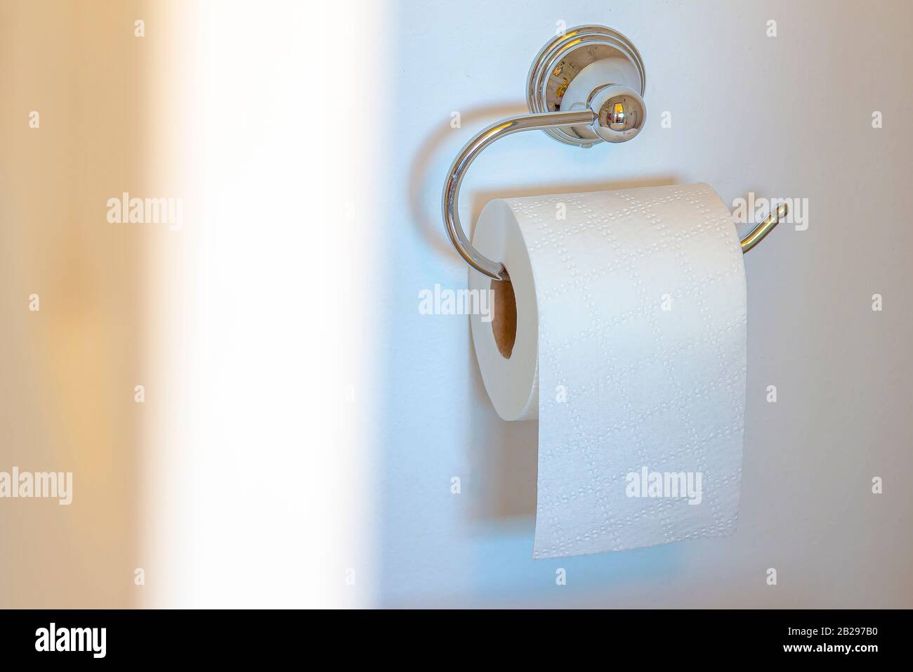 Single Post Toilet Paper Holder on a white wall background with soft shadow and defucus door Stock Photo