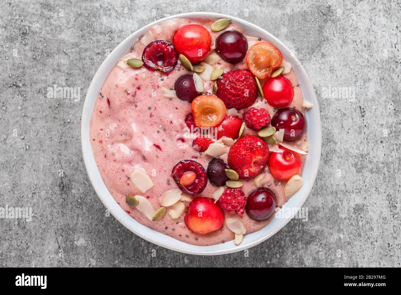 smoothie bowl or nice cream made of frozen bananas and berries with fresh berries, nuts and seeds. healthy breakfast. top view Stock Photo