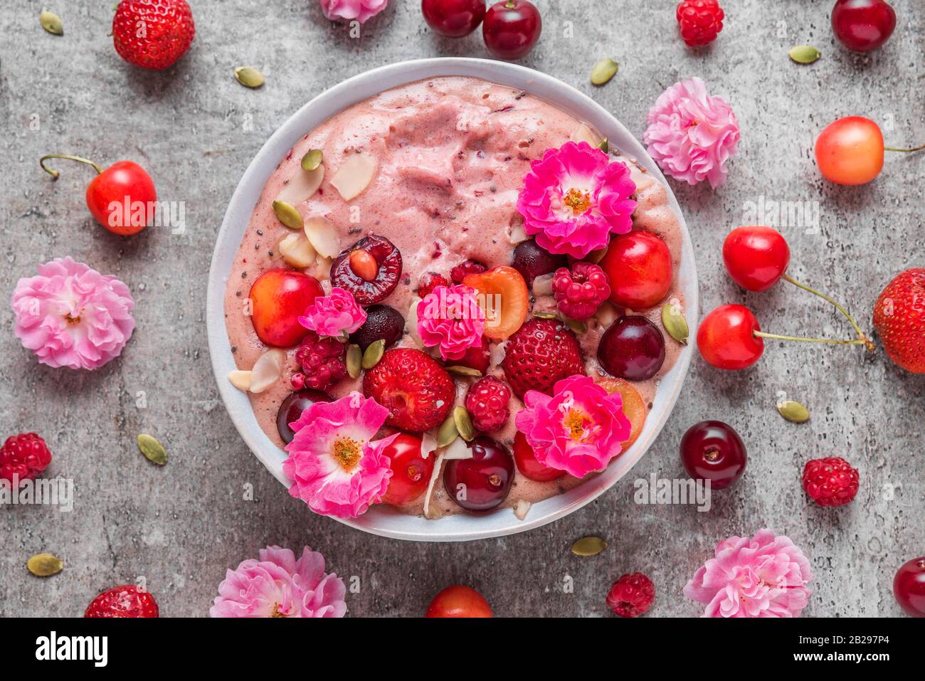healthy breakfast dessert. smoothie bowl or nice cream with fresh berries, nuts, chia seeds and rose flowers. top view Stock Photo