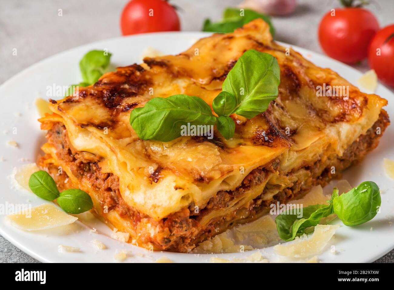 Homemade meat lasagna with fresh basil and parmesan cheese in a plate on white wooden table. close up. italian food. Stock Photo