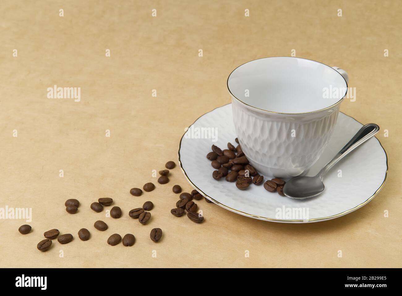 Empty white coffee cup with gold border and coffee seeds on the table. close up Stock Photo
