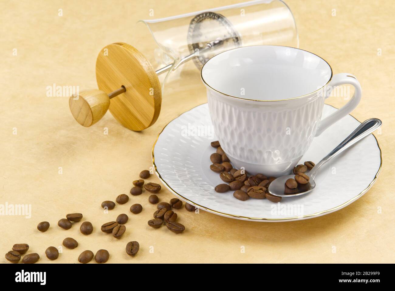 Empty white coffee cup with gold border and coffee seeds on the table. close up Stock Photo