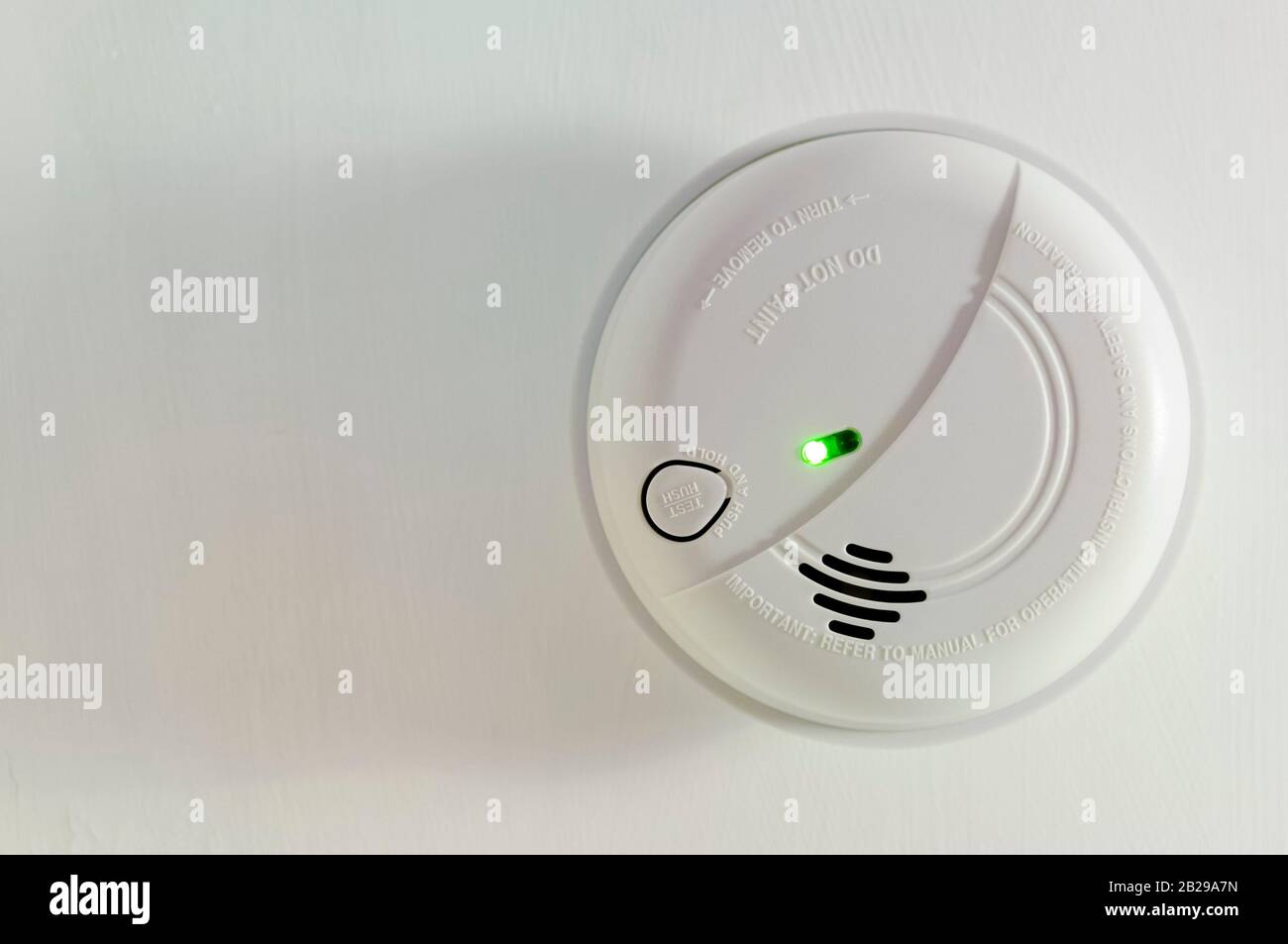 Domestic, round, home smoke alarm, with green light, fitted to a ceiling Stock Photo