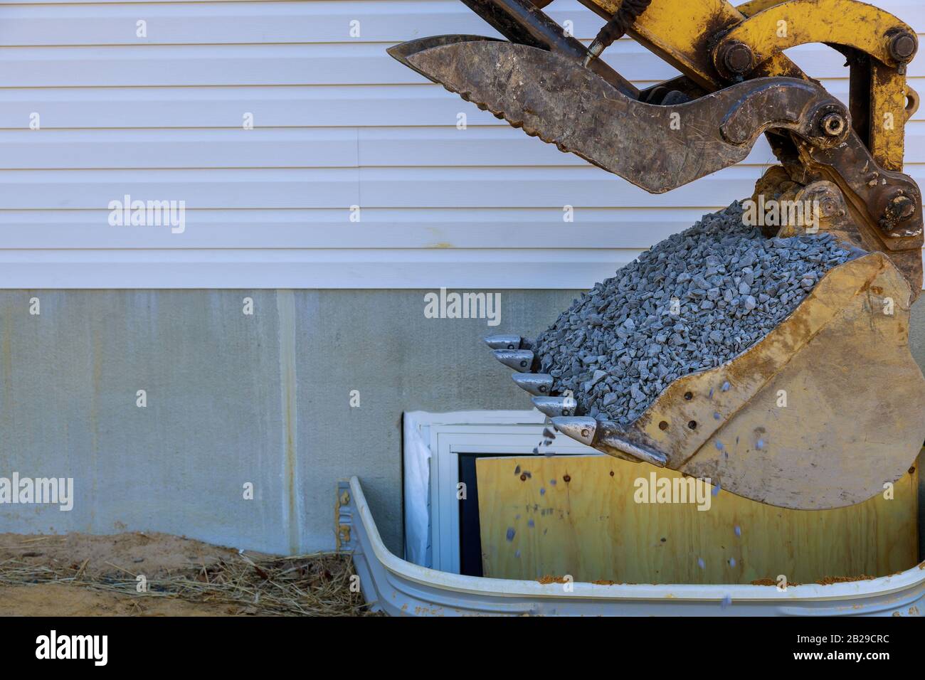 Bucket standing on gravel stones, new house under construction window