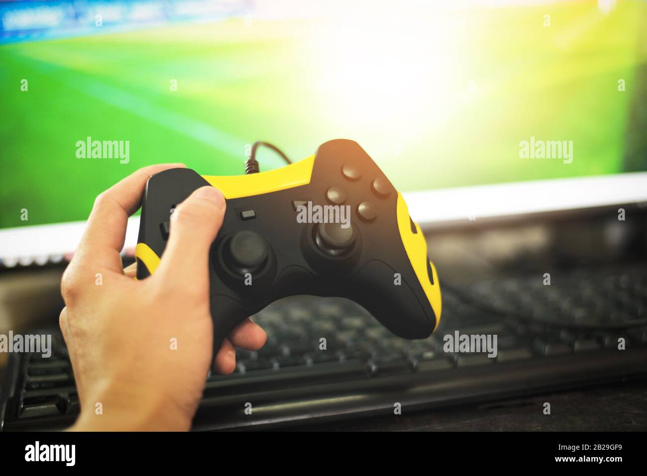 Gamer and guy controller with game pad joystick on hand playing gaming and watching video on tv or Computer games console / The boy holding hobby play Stock Photo