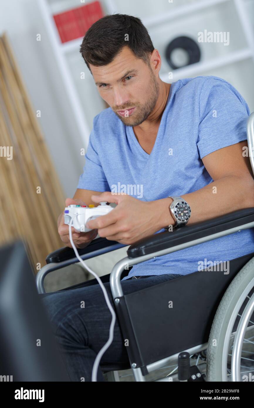 man in wheelchair playing video games at home Stock Photo Alamy