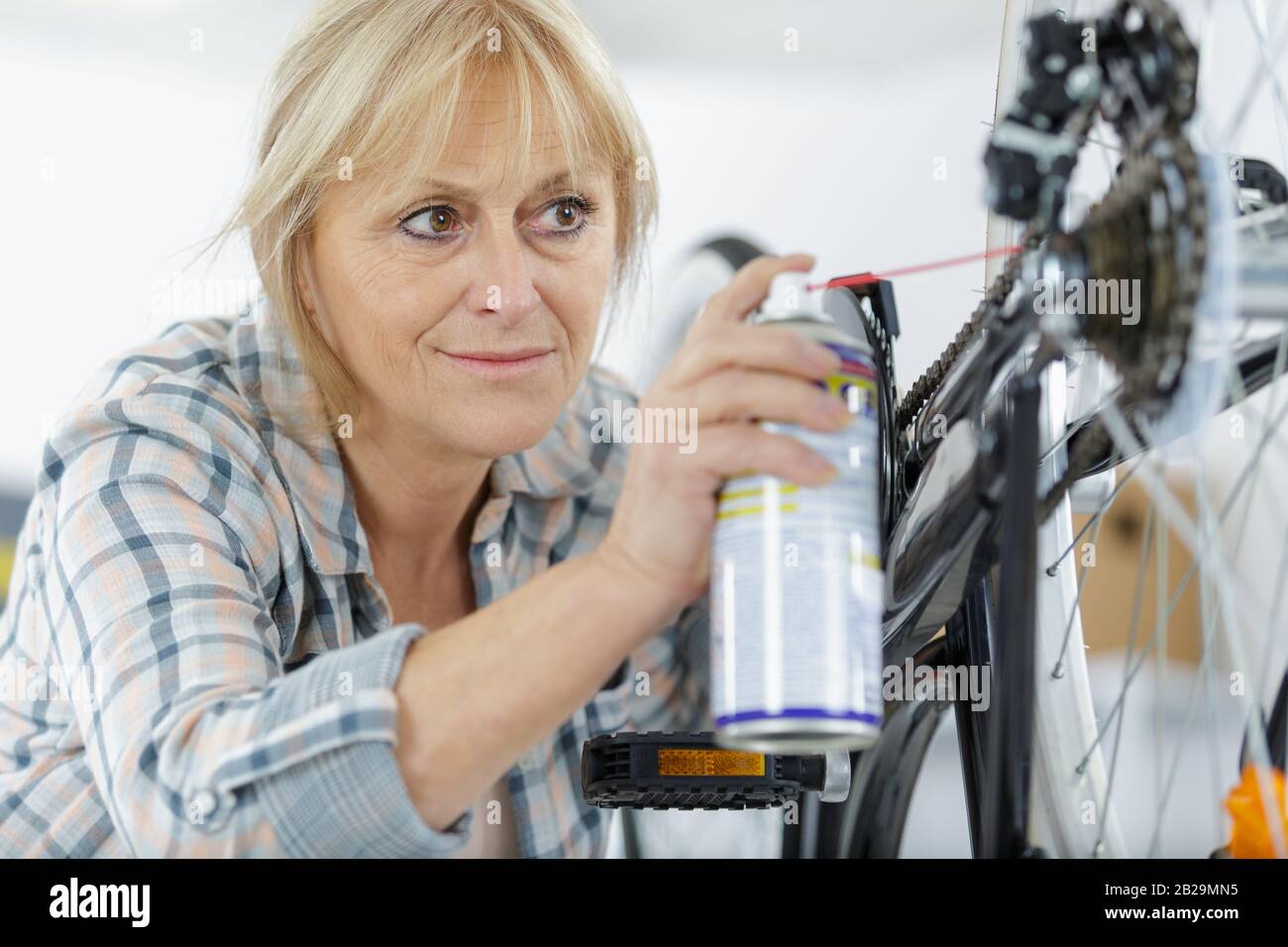 female mature mechanic oiling bicycle chain Stock Photo