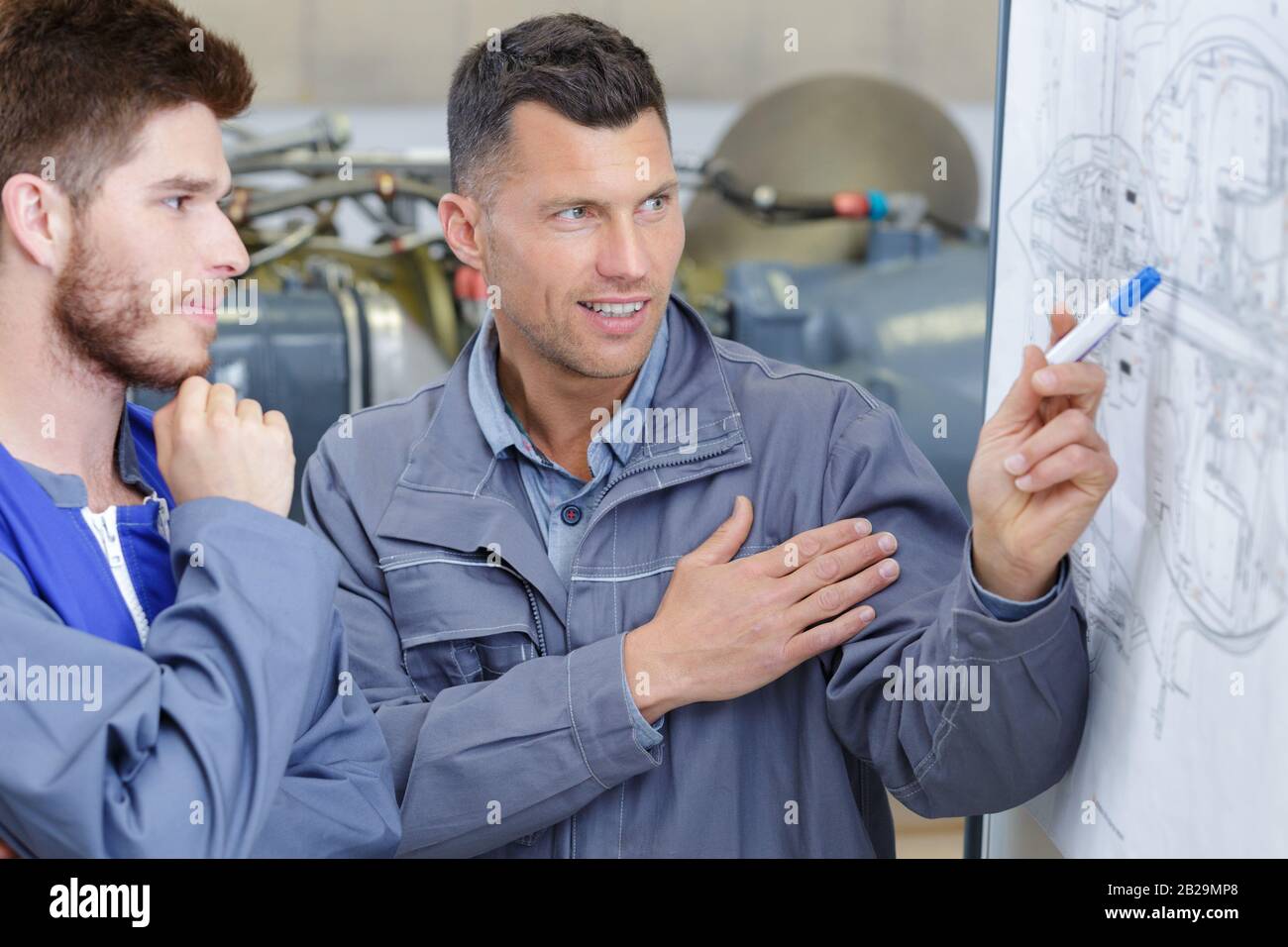 engineer and his apprentice looking at detailed drawings Stock Photo