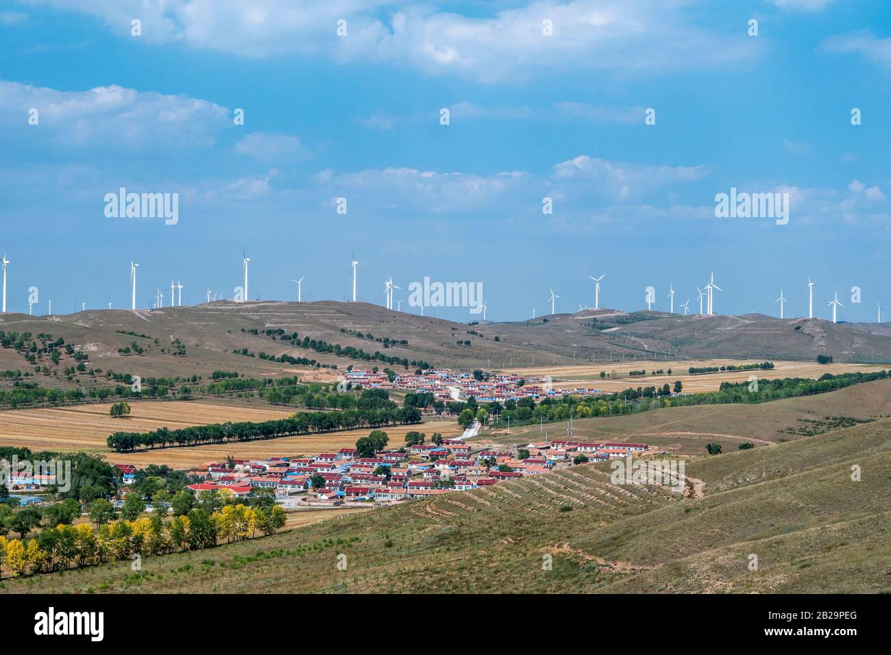 Wind turbines on rolling hills and town, Taipusi Banner, Inner Mongolia, China Stock Photo