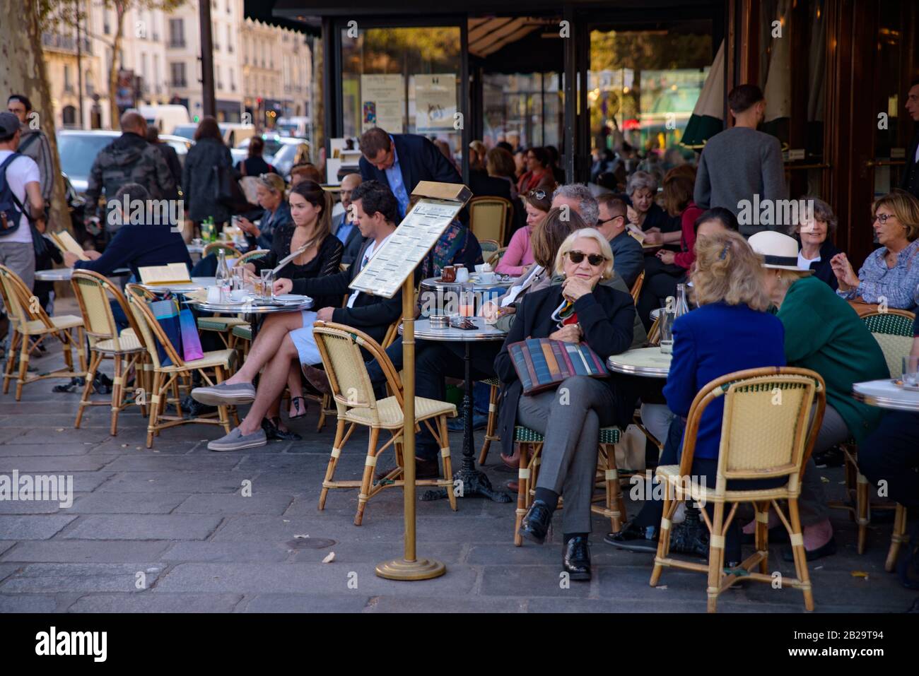 People having coffee at outdoor seating of cafe in Paris, France Stock Photo