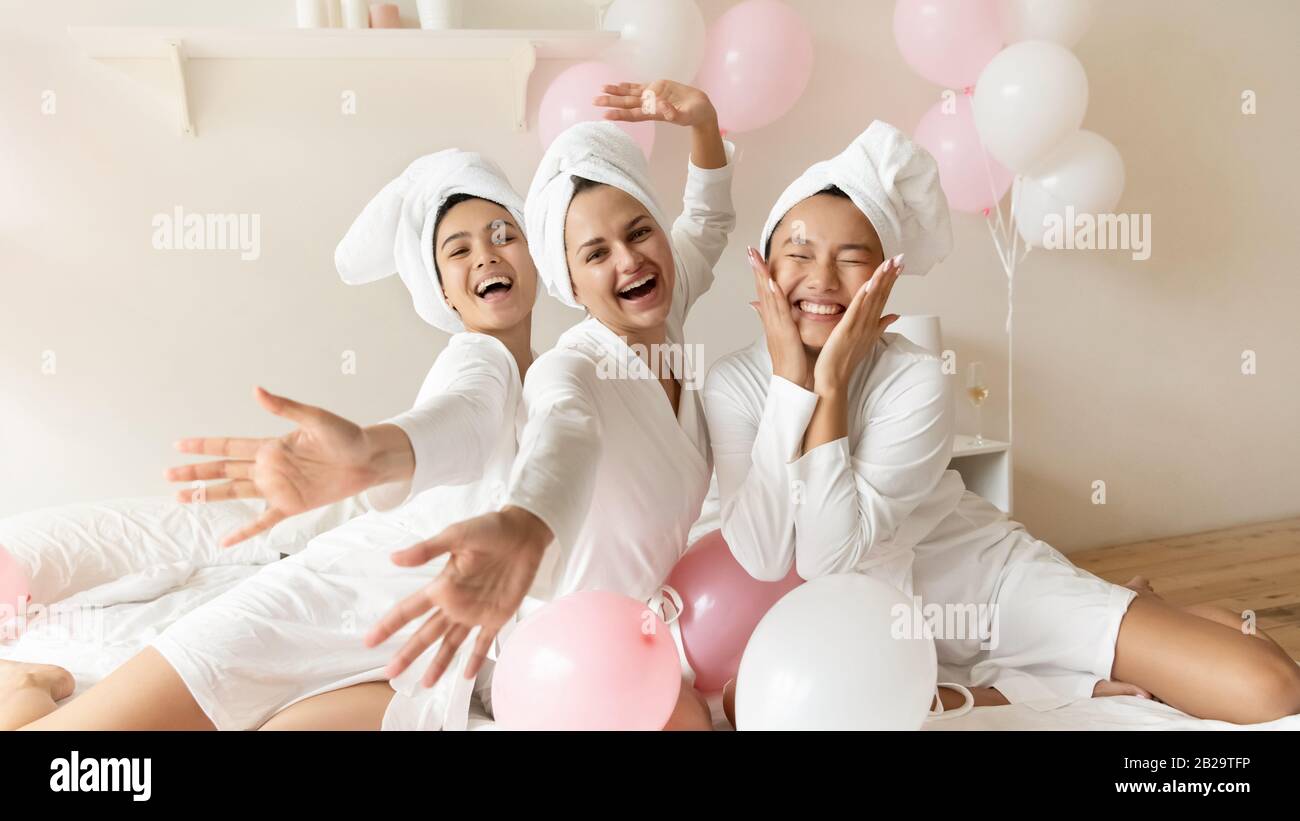Portrait funny Asian bride with bridesmaids sitting on bed Stock Photo