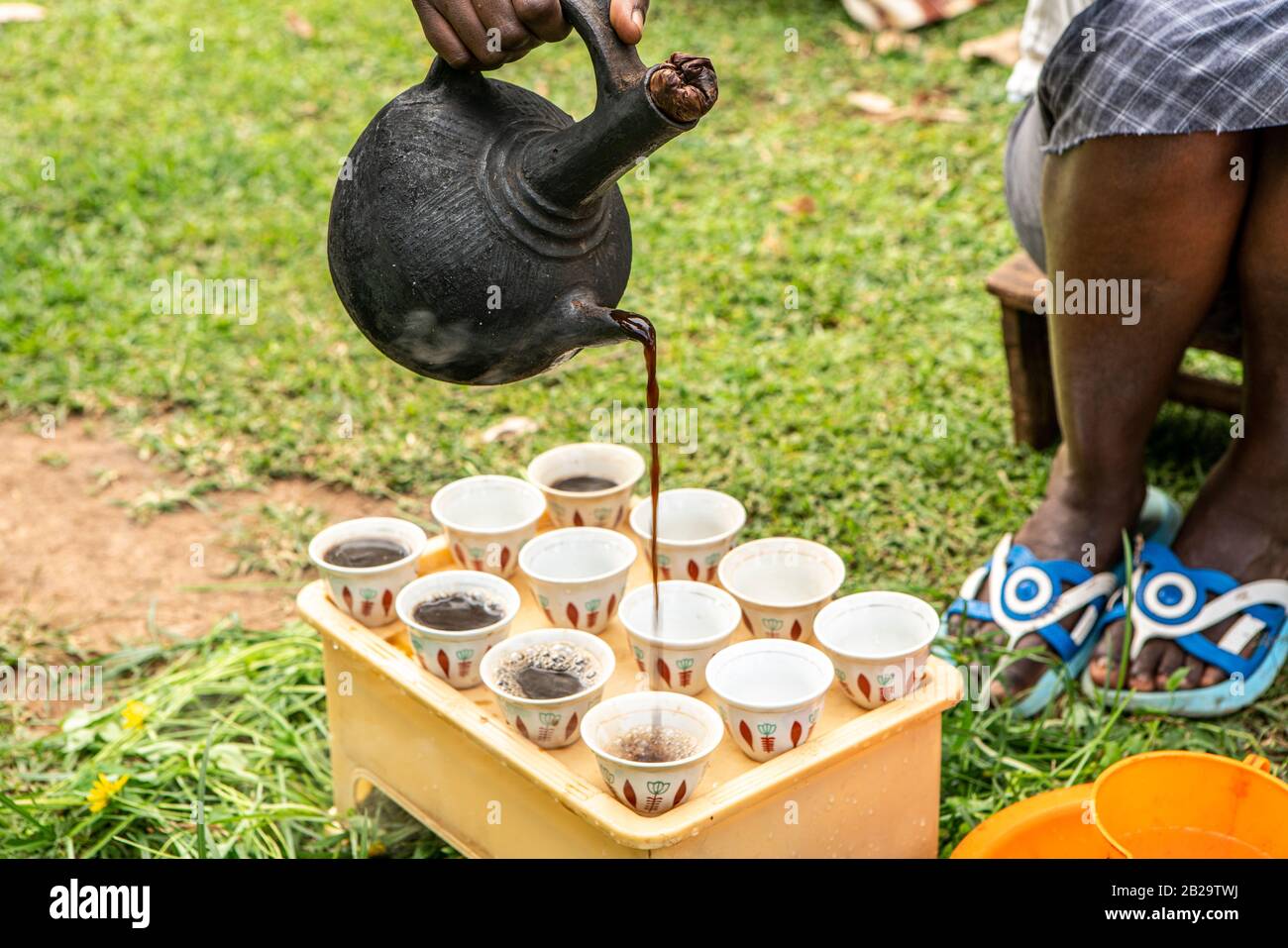Woman pouring traditionally brewed coffee into finjal - coffee cup - from a jebena - coffee pot in a village in southern Ethiopia Stock Photo
