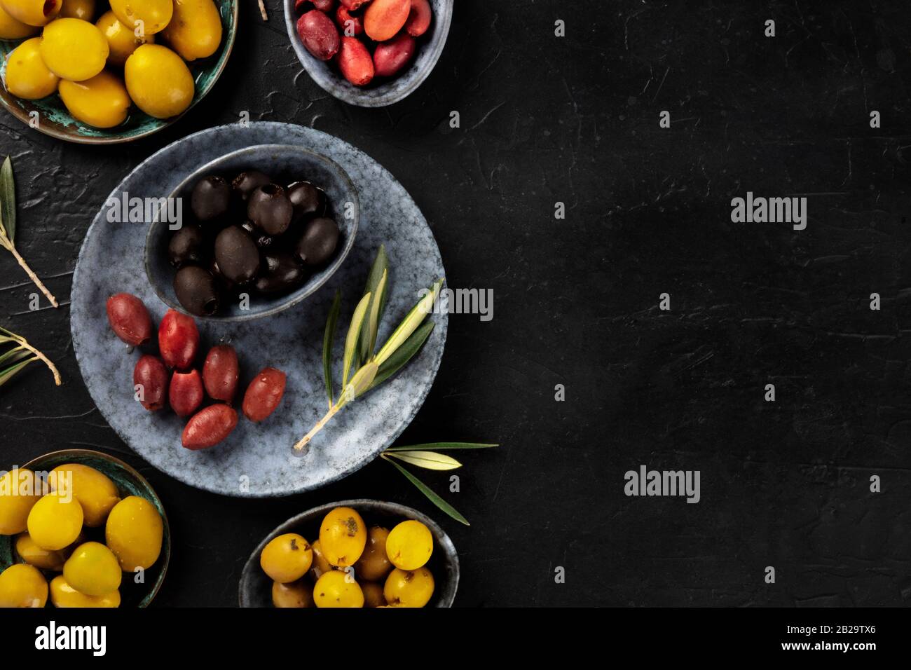 Olives, green, black and red, an assortment with leaves on a dark background with a place for text, shot from above Stock Photo