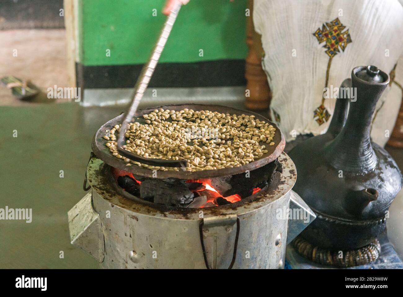 Roasting of green immature coffee beans on a flat pan in a house in southern Ethiopia Stock Photo