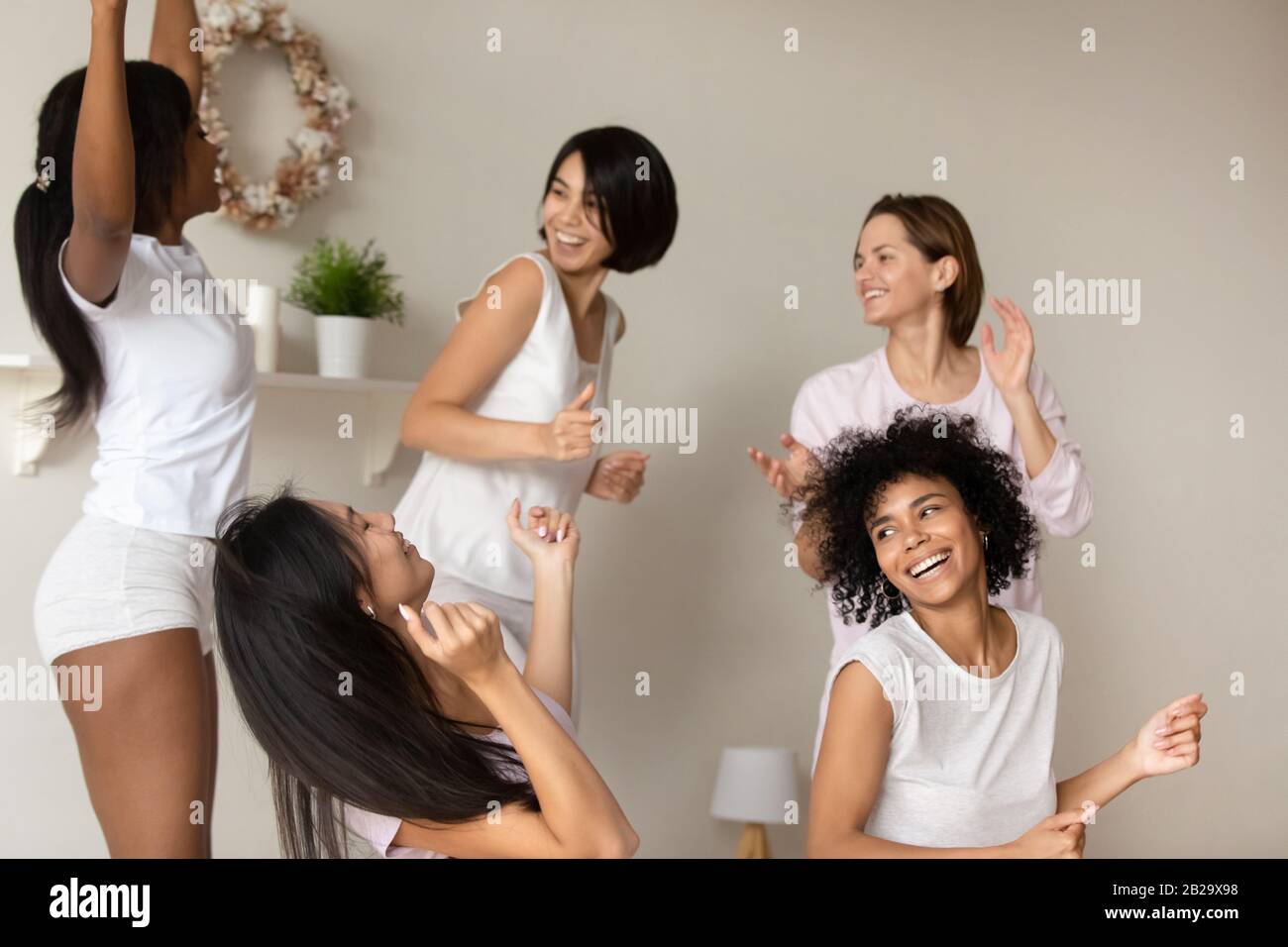 Pretty African American girl dancing with friends at sleepover party Stock Photo