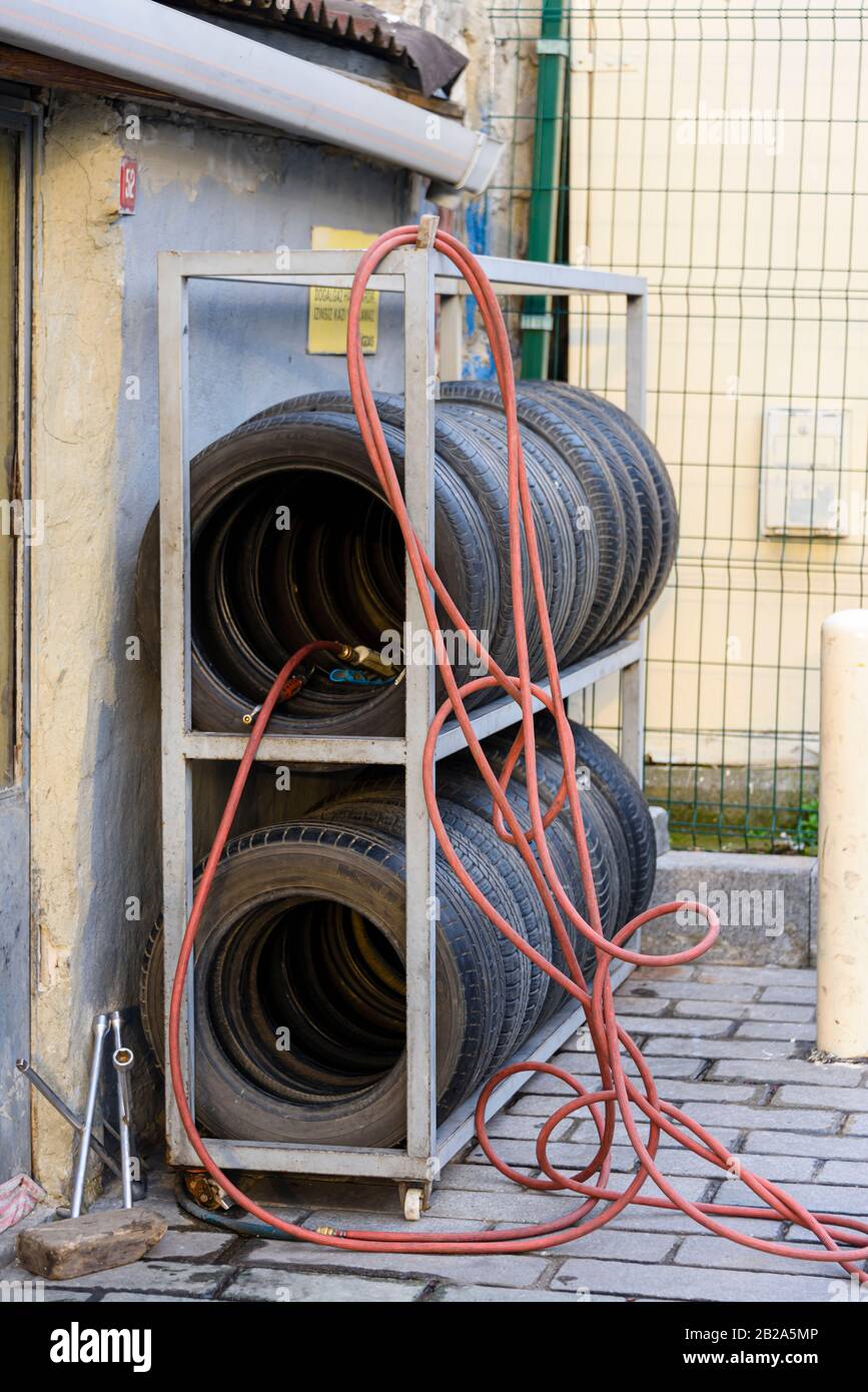 Tyres, pneumatic hose and tools outside a tyre repair shop. Stock Photo