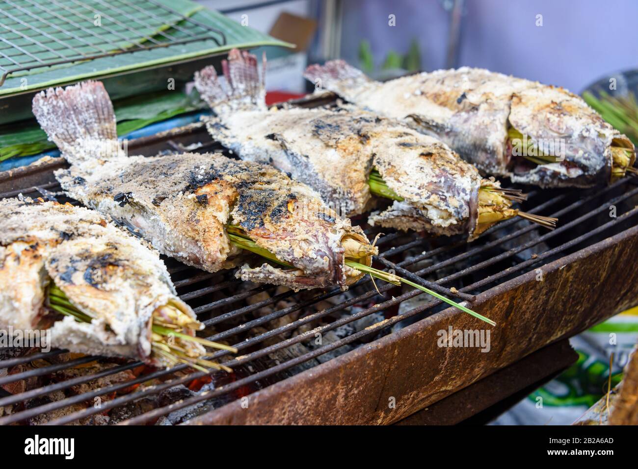 Salted fish with lemongrass being cooked on a barbeque grill at a street food stall, Bangkok, Thailand Stock Photo
