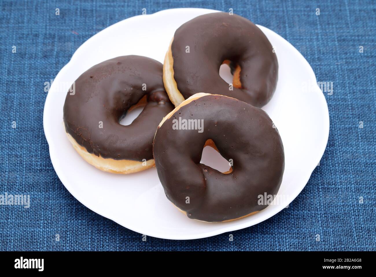 Donut with chocolate on a plate on table. Close-up Stock Photo