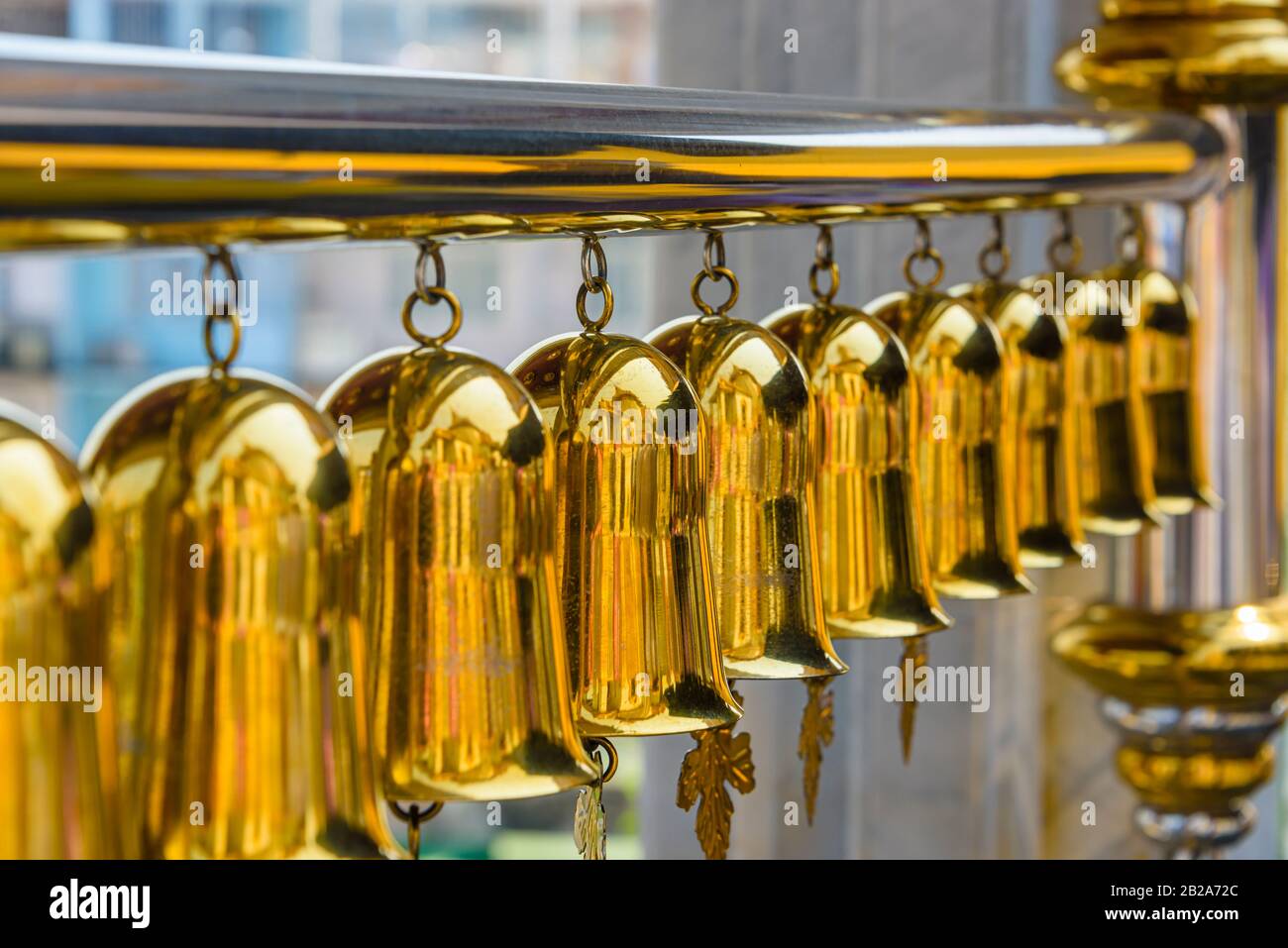 Row of brass bells wind chimes at Wat Songkhram, Bangkok, Thailand Stock Photo