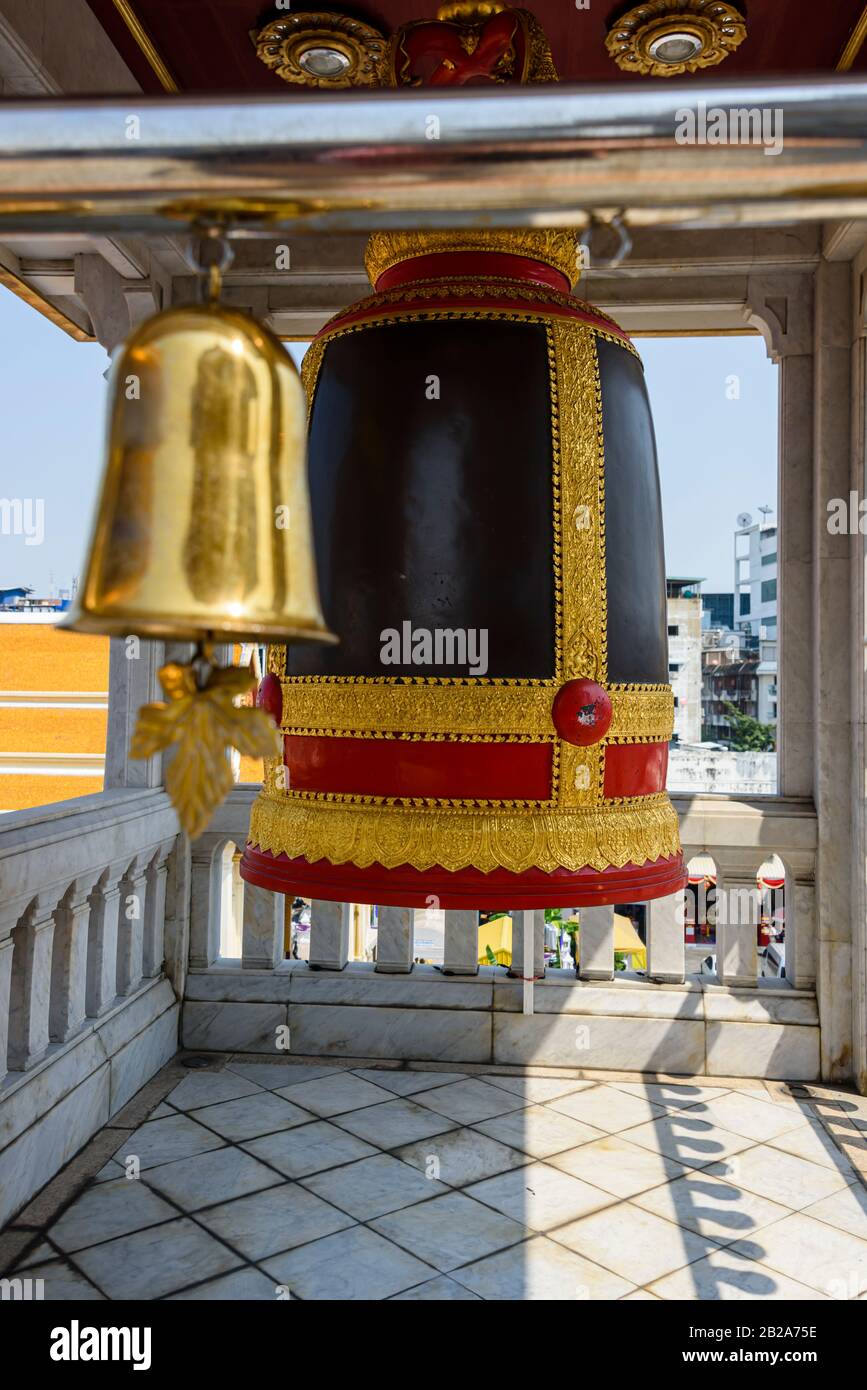 Brass bell wind chime in front of a large bell at Wat Songkhram