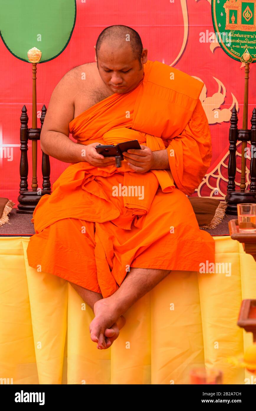 A Buddhist monk uses his smartphone, Wat Pho, Bangkok, Thailand Stock Photo