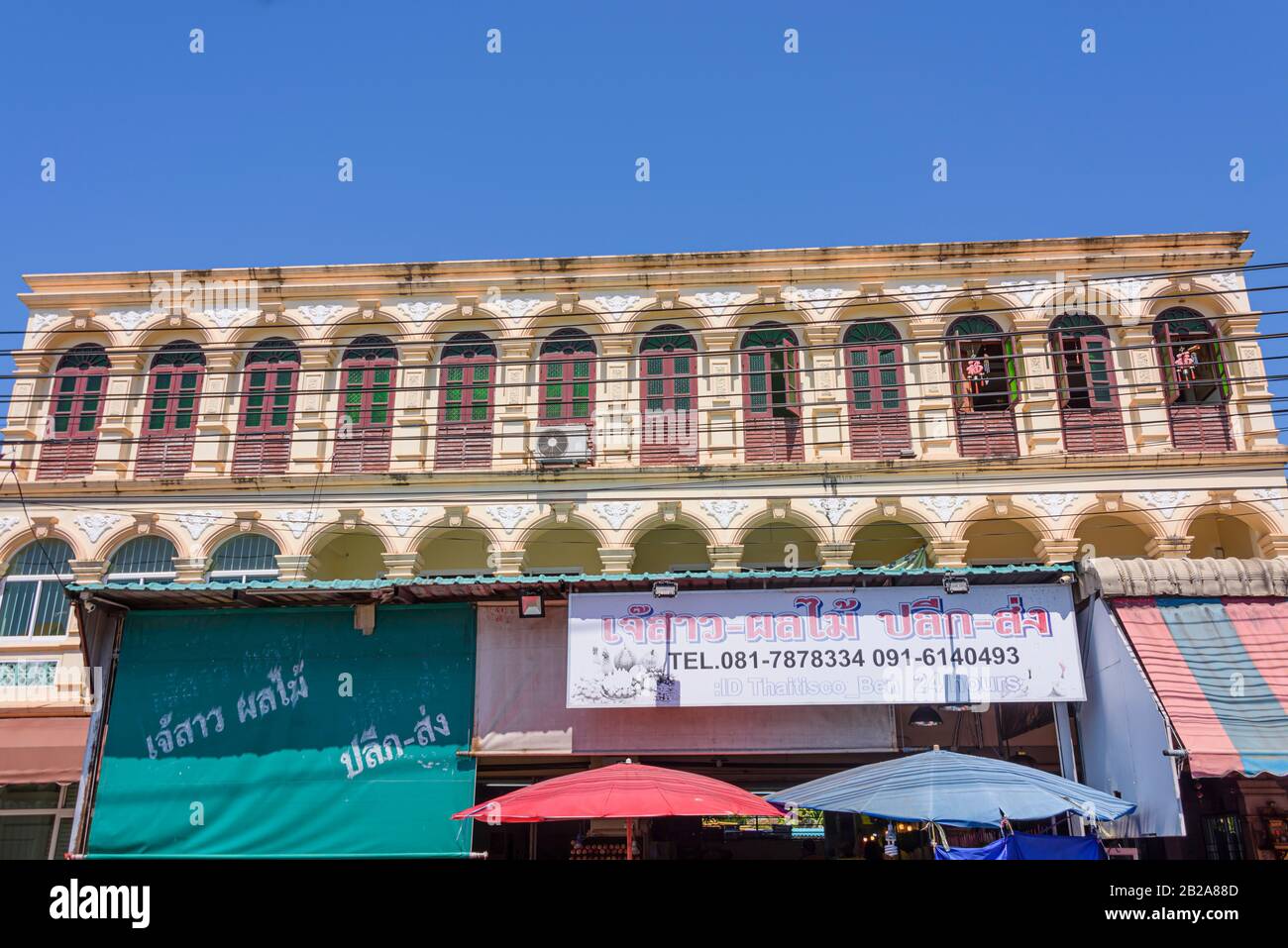 Electrical cables stretched in front of a Sino-Portuguese building with many windows, Thailand Stock Photo