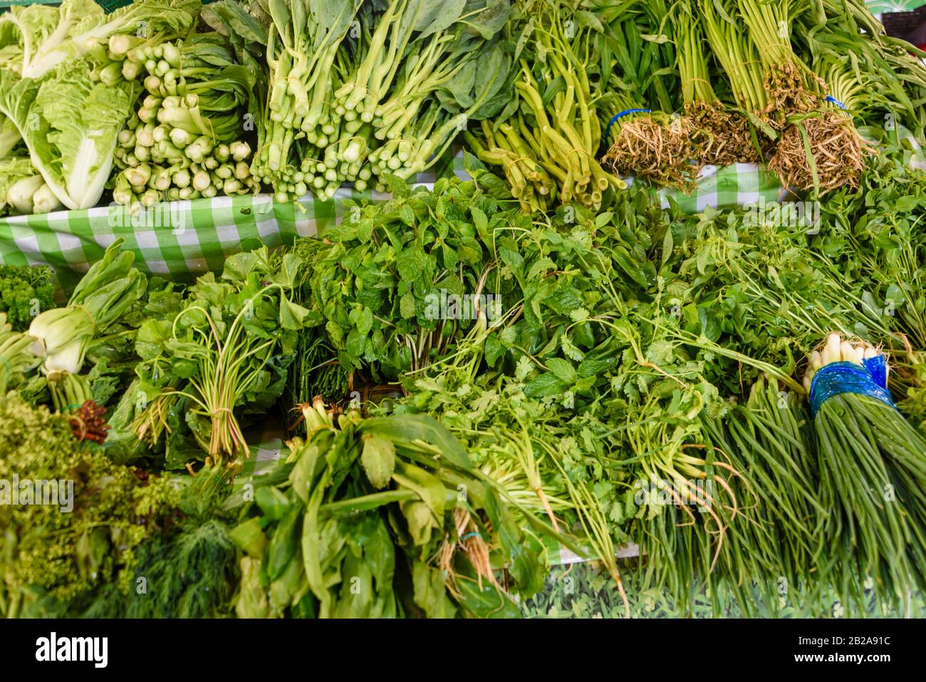 Green vegetables including spring onions, pok choi and morning glory on sale in the traditional Mae Somchit Kata Fresh Market, Kata, Phuket, Thailand Stock Photo