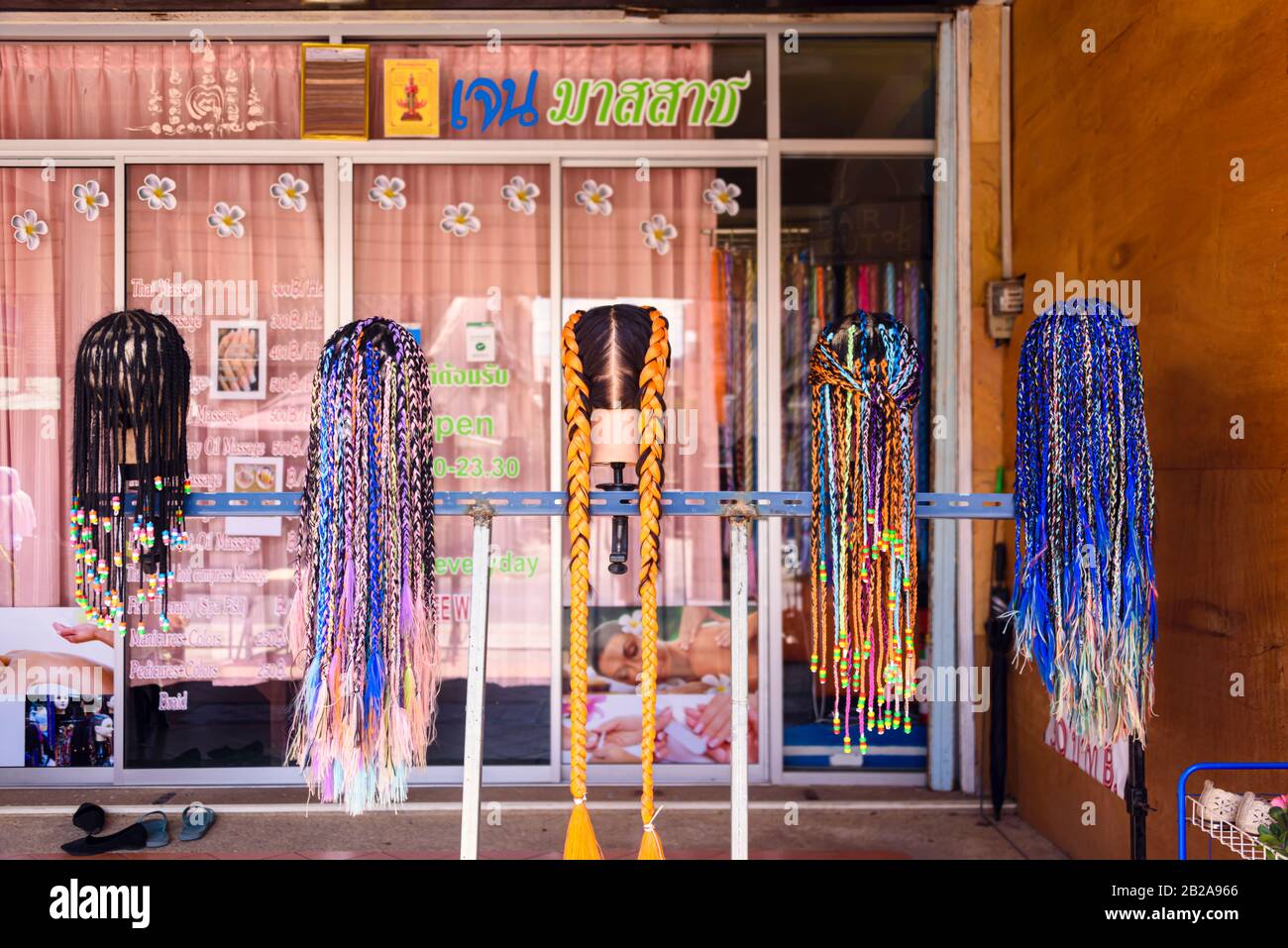 Five heads outside a hairdressers showing hair braids, Thailand. Stock Photo