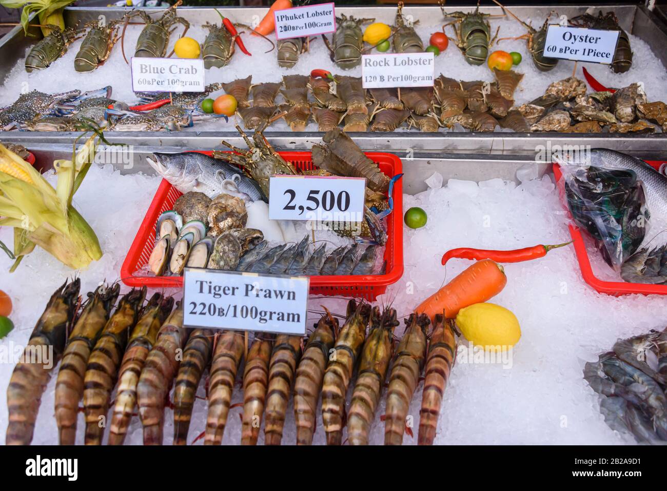 Large Tiger Prawns, fish, shellfish, lobster, crabs on ice for sale at a street food market stall in Phuket, Thailand Stock Photo