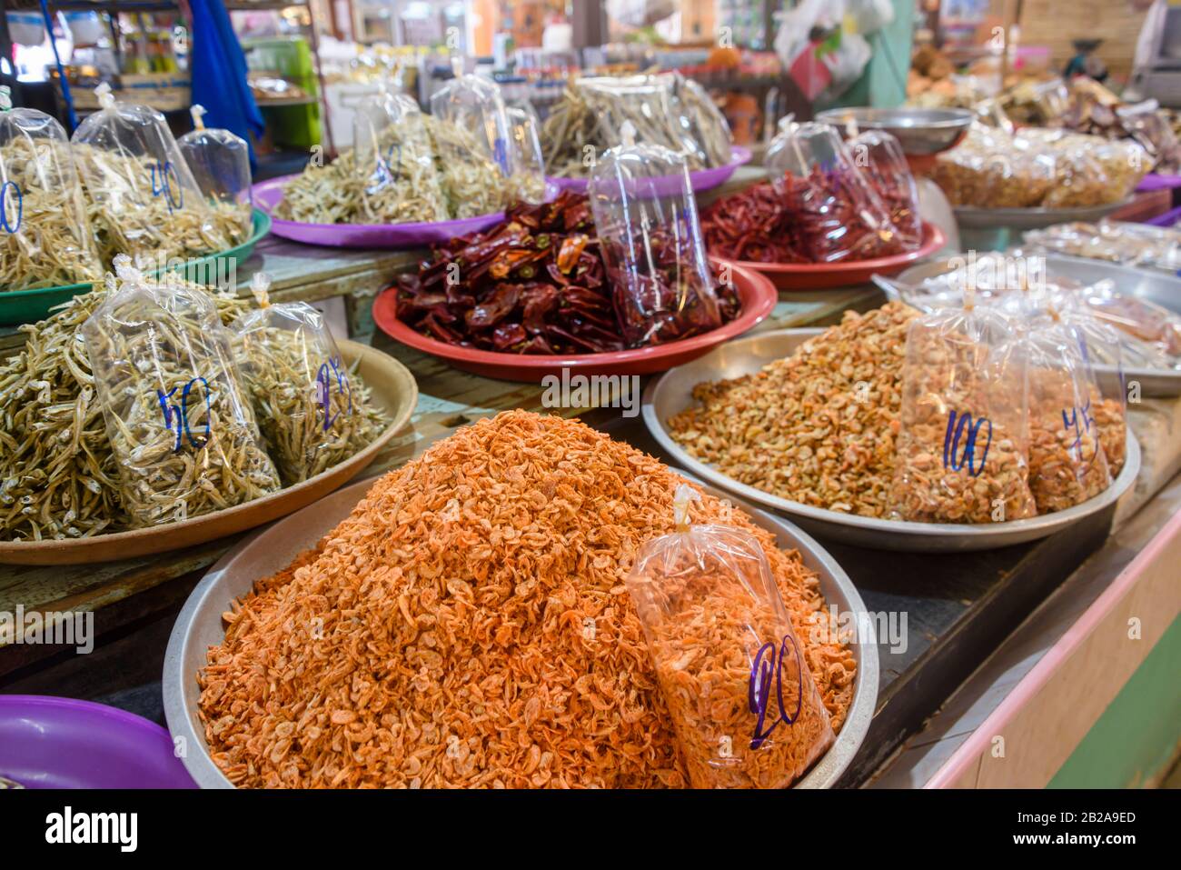 Bowls of cooked shrimp, prawns, anchovies and chilies for sale at a food market stall in Thailand Stock Photo