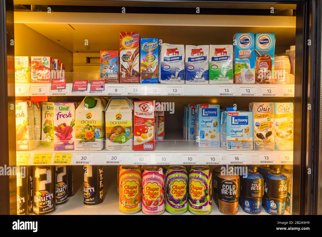 Fridge with cold drinks including lactose free milk, Chupa Chups, and  cold brew coffee in a supermarket in Thailand Stock Photo