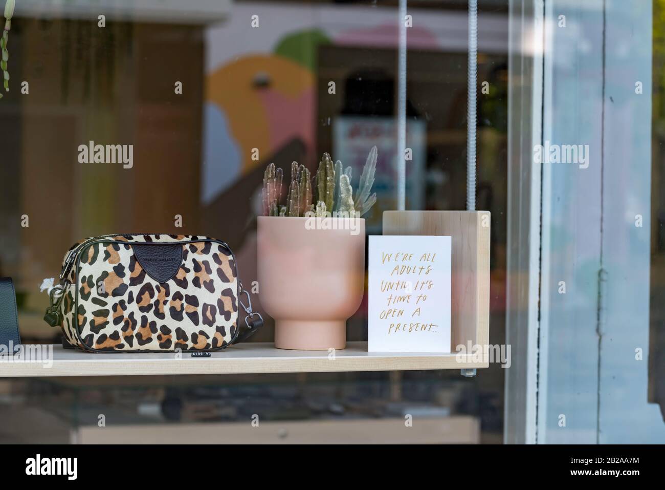 A leopard skin purse and a humorous small Christmas sign in a store window in Fitzroy, Melbourne, Australia Stock Photo