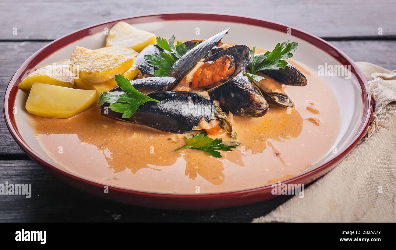 Food banner. Mussels and fried potatoes in sweet and sour sauce on a dark wooden table. Stock Photo