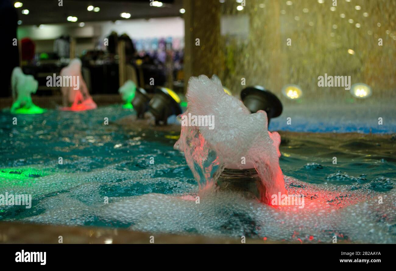 Blurred water background. Backlit water jet in the fountain. Stock Photo