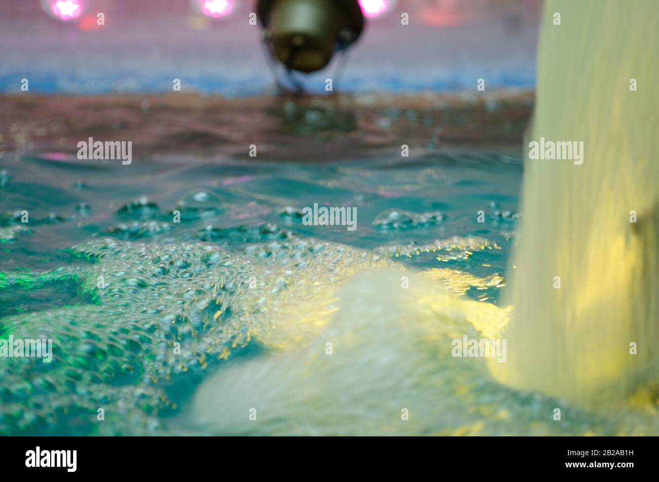 Blurred water background. Backlit water jet in the fountain. Stock Photo