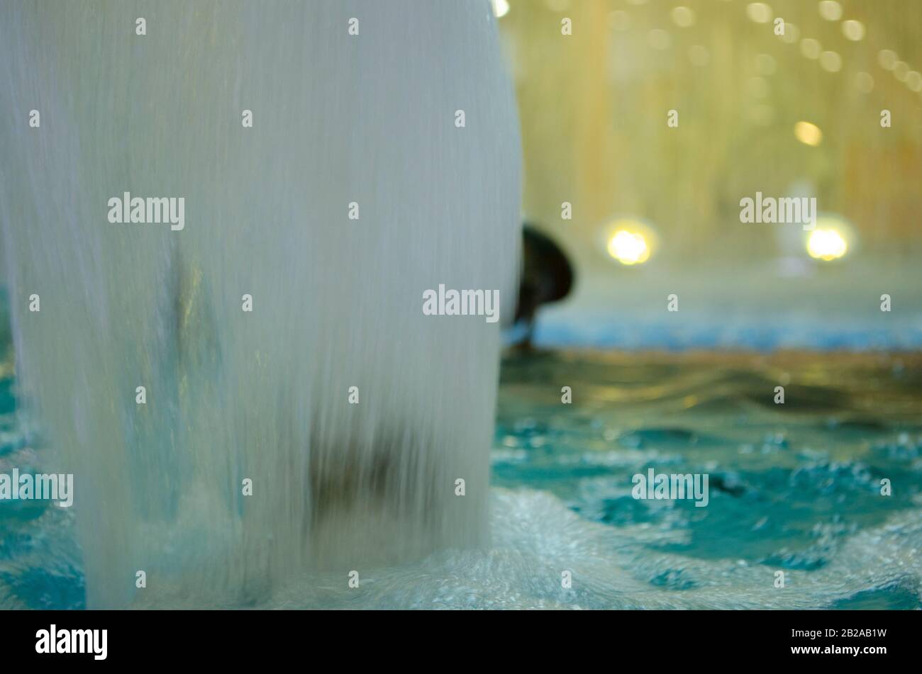Blurred water background. Backlit water jet in the fountain. Stock Photo