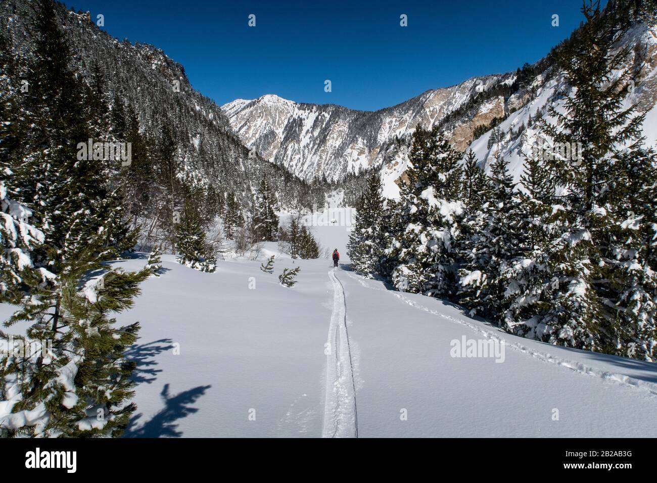 A man ski tours through the Vallée des Avals near the French alpine resort of Courchevel after fresh snowfall on a sunny day. Stock Photo