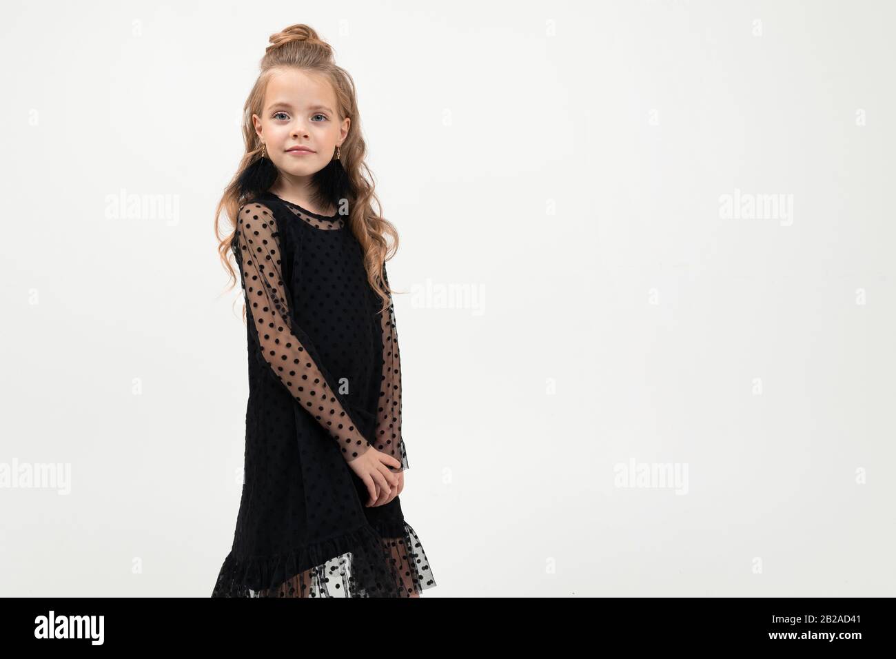 Pretty little girl in black dress stands isolated on white background ...